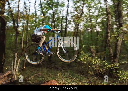 Ein junger Kerl in einem Helm fliegt auf einem Fahrrad, nachdem er von einem Kicker gesprungen ist Stockfoto