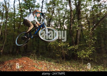 Ein junger Kerl in einem Helm fliegt auf einem Fahrrad, nachdem er von einem Kicker gesprungen ist Stockfoto