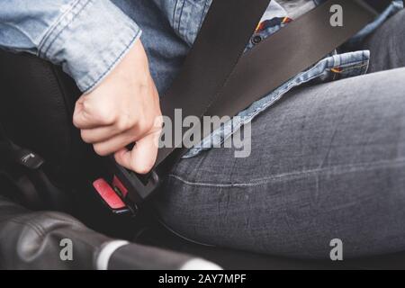 Die weiblichen Hände legen den Sicherheitsgurt im Auto an. Stockfoto