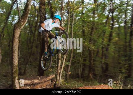 Ein junger Kerl in einem Helm fliegt auf einem Fahrrad, nachdem er von einem Kicker gesprungen ist Stockfoto