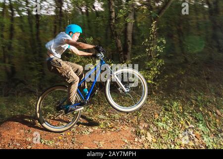 Ein junger Kerl in einem Helm fliegt auf einem Fahrrad, nachdem er von einem Kicker gesprungen ist Stockfoto