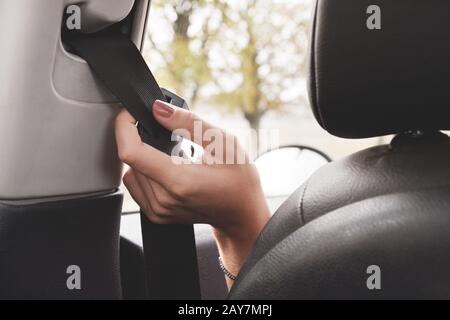 Die Hand einer Frau greift hinter ihren Sicherheitsgurt, um ihn zu befestigen. Stockfoto