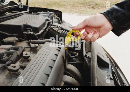 Das Mädchen, das die Haube ihres Autos öffnet, überprüft den Motorölstand Stockfoto