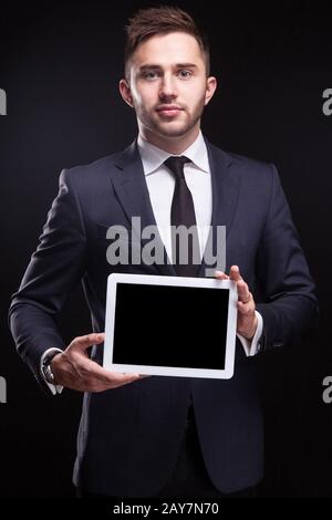 Ein Bild von einem ernsthaften Unternehmer, der mit einem Tablet steht Stockfoto