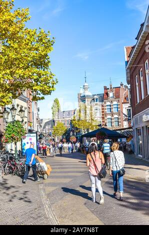 Venlo, Limburg-Niederlande - 13. Oktober 2018: Einkaufsstraße im historischen Zentrum der niederländischen Stadt. Menschen, die auf der Straße, dem historischen Platz im Hintergrund, spazieren gehen. Vertikales Foto. Stockfoto