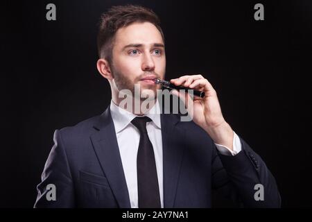 Bild eines ernsthaften Geschäftsmannes, der mit einem Vaping-Gerät steht Stockfoto