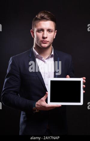 Ein Bild von einem ernsthaften Unternehmer, der mit einem Tablet steht Stockfoto