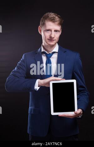 Ein Bild von einem ernsthaften Unternehmer, der mit einem Tablet steht Stockfoto