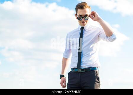 Seriöser junger Busunessman in weißem Hemd, Krawatte und Sonnenbrille Stockfoto