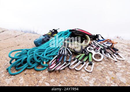 Kletterausrüstung - Seil- und Carbinenblick von der Seitennaht. Ein auf dem Boden liegendes gewickeltes Kletterseil als Hintergrund. Stockfoto