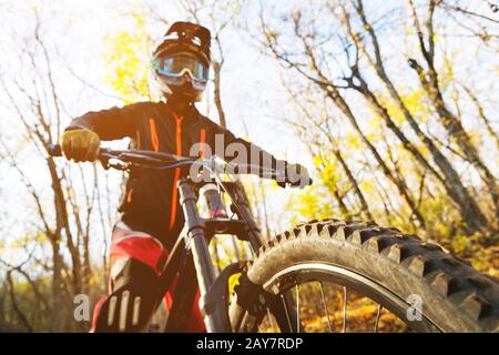 Porträt eines jungen Fahrers in vollem Schutz einer Gesichtshelmmaske und Handschuhe auf einem Fahrrad Stockfoto