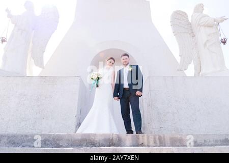 Porträt eines schönen Paares, das an einem Hochzeitstag mit einem Blumenstrauß in der Hand vor dem Hintergrund eines orthodoxen Christen gegraben wurde Stockfoto