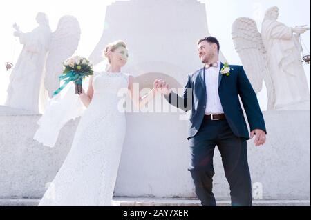 Porträt eines schönen Paares, das an einem Hochzeitstag mit einem Blumenstrauß in der Hand vor dem Hintergrund eines orthodoxen Christen gegraben wurde Stockfoto