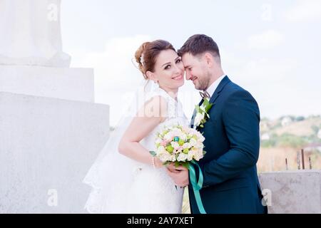 Porträt eines schönen Paares, das an einem Hochzeitstag mit einem Blumenstrauß in der Hand vor dem Hintergrund eines orthodoxen Christen gegraben wurde Stockfoto