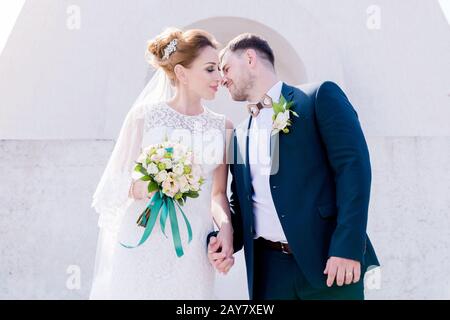 Porträt eines schönen Paares, das an einem Hochzeitstag mit einem Blumenstrauß in der Hand vor dem Hintergrund eines orthodoxen Christen gegraben wurde Stockfoto