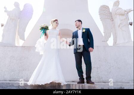 Porträt eines schönen Paares, das an einem Hochzeitstag mit einem Blumenstrauß in der Hand vor dem Hintergrund eines orthodoxen Christen gegraben wurde Stockfoto