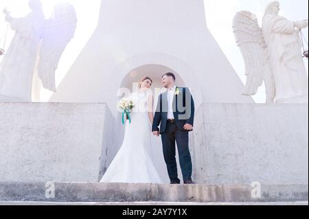 Porträt eines schönen Paares, das an einem Hochzeitstag mit einem Blumenstrauß in der Hand vor dem Hintergrund eines orthodoxen Christen gegraben wurde Stockfoto