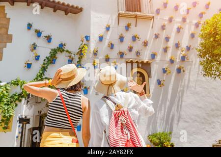 Zwei Mädchen Touristen bewundern einen tollen Blick auf Blumentöpfe an den weißen Wänden in der berühmten Blumenstraße in Andalusien Stockfoto