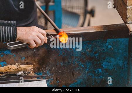 Künstler Man Hands Closeup Arbeitet an einer Form eines heißen Glases in der Werkstatt Stockfoto