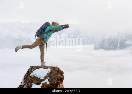 Ein fröhliches lächelndes Flusspferd reist in einer Daunenjacke mit Rucksack und steht in einem großen Fellhut in einer Superman-Flugposition Stockfoto