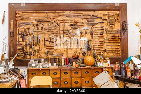 Verschiedene alte Vintage-Werkzeuge auf dem Brett in der Lederhandwerkswerkstatt, Handarbeitskonzept Stockfoto