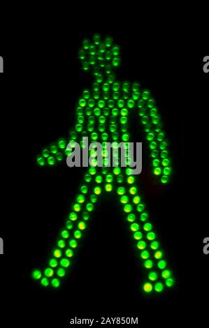 Grünes Licht des Hinweisschildes zum Fußgängerübergang auf schwarzem Grund Stockfoto