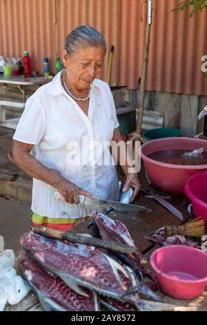 Brisas de Zicatela, Oaxaca, Mexiko - EINE Frau arbeitet an ihrem Stand am Straßenrand und bereitet frische Fische aus dem Pazifischen Ozean zu. Stockfoto