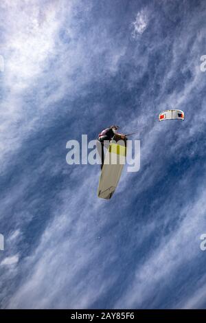 Ein sportliches Kitesurfing, das Frauen in der Luft fliegt und einen Trick zum greifen des Boards ausführt. Kitesurfen. Keine Logos Stockfoto