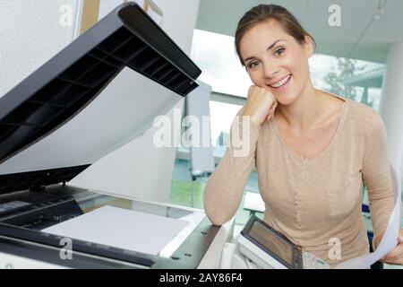 Fröhliche Geschäftsfrau mit Kopierer Stockfoto