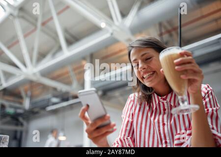 Junge Brunette textet auf einem Handy im Restaurant. Multitasking, Freizeit, Joj, Konzept Stockfoto
