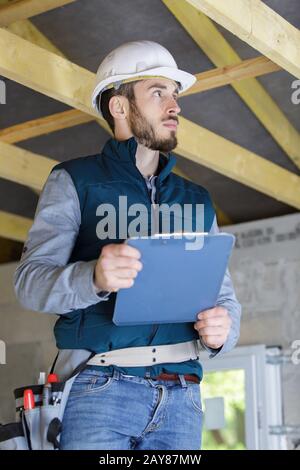 Bauinspektor auf einer Leiter, die eine Zwischenablage hält Stockfoto