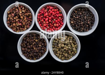 Fünf verschiedene Pfefferkörner in Töpfen, Stockfoto