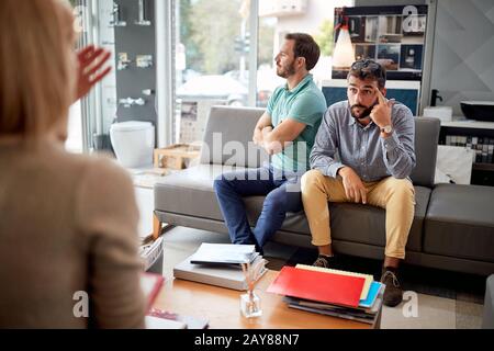 Unzufriedene junge Kunden mit Verkäufern im Laden für das Haus. Stockfoto