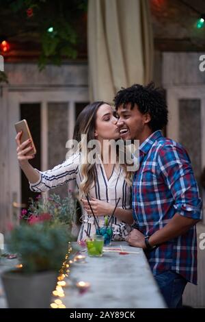 Kaukasische Frau und afro-amerikanischer Mann nehmen selfie in eine Bar im Freien, multiethnische, Freunde, Paar, selfie, Konzept Stockfoto