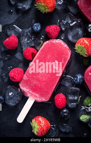 Erfrischender Popsicle auf Eiswürfeln und Früchten Stockfoto