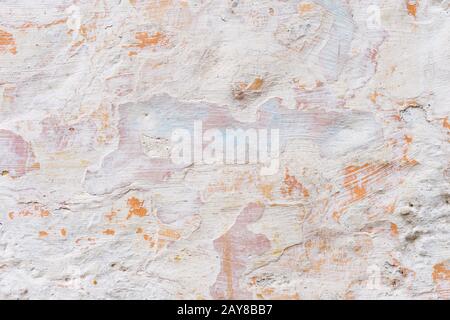 Strukturierter Grunge-Hintergrund. Volumetrisch verputzte Wand mit einer mehrschichtigen, rissigen Beschichtung. Orangefarbene Späne an der weiß getünchten Wand. B. Stockfoto