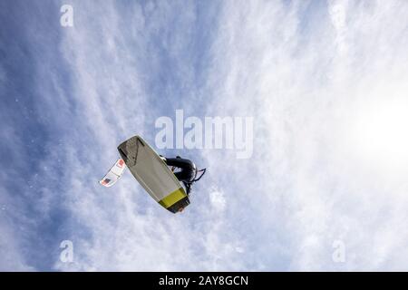 Kitesurfen oder Kiteboarden, die hoch oben mit einem Bretter greifen Trick springen, ihr Kite direkt über ihr. Keine Logos Stockfoto