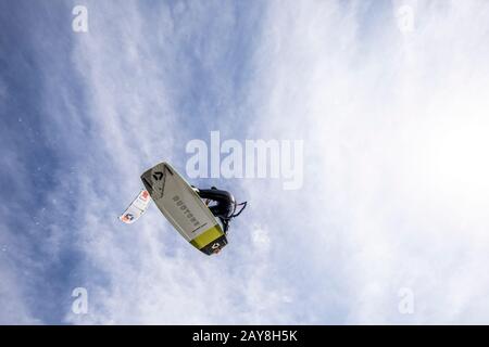 Kiteboarden Frauen fliegen von einem Hochsprung mit ihrem Drachen direkt über ihr über den Kopf. Cirrus Wolken Im Hintergrund. Redaktionelle Version des Fotos. Stockfoto
