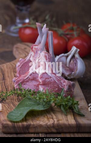 Rohe Lammkoteletts mit Kräutern auf Holz Stockfoto