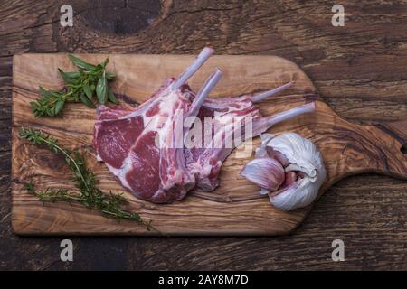 Rohe Lammkoteletts mit Kräutern auf Holz Stockfoto