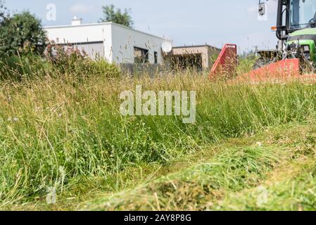 Bauer mäst eine Wiese mit Traktor und Frontmäher Stockfoto