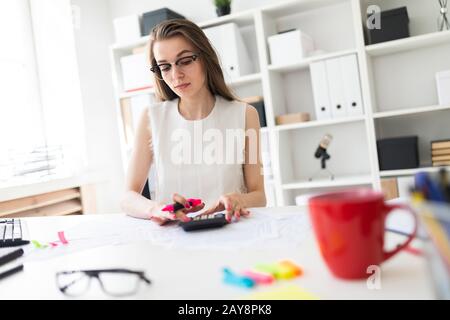 Ein junges Mädchen im Büro hält eine rosa Marker in die Hand und zählt auf einen Rechner. Stockfoto