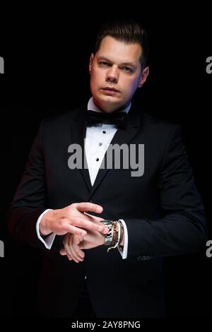 Portrait von zuversichtlich Schöne elegante stilvolle Geschäftsmann mit Bow-tie mit Hand auf Hand auf schwarzen Hintergrund im Studio Stockfoto