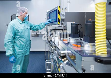 Apotheke Industrie Fabrik mann Arbeiter in Schutzkleidung in sterilen Arbeitsbedingungen auf pharmazeutische Ausrüstung Stockfoto