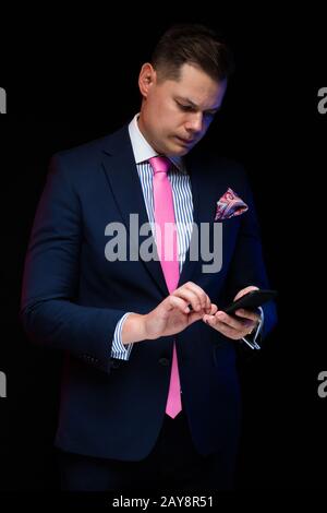 Portrait von zuversichtlich stattliche Schwere elegante Geschäftsmann holding Telefon in seine Hände auf schwarzem Hintergrund Stockfoto