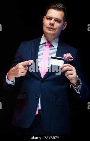 Portrait von zuversichtlich Schöne elegante Geschäftsmann holding Kreditkarte in der Hand auf schwarzem Hintergrund Stockfoto