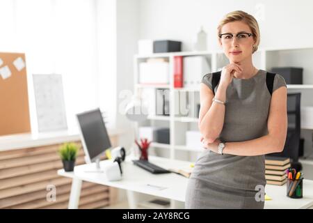 Ein junges Mädchen in Gläser steht in der Nähe eine Tabelle im Büro. Stockfoto