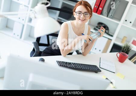 Schöne junge Mädchen im Büro Arbeiten mit Dokumenten, Blick auf den Monitor und eine Flasche Wasser. Stockfoto