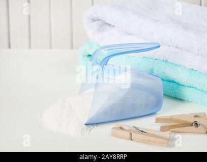 Handtücher, Waschpulver in Messbecher und Holzkleidereppen Stockfoto