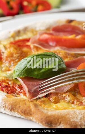 Detail einer Pizza mit Schinken und Basilikum Stockfoto